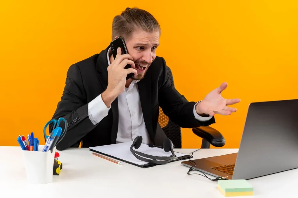 frustrated handsome businessman suit working laptop talking mobile phone looking confused displeased sitting table offise orange background 141793 53847